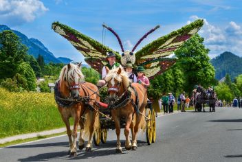 Bunter Festumzug mit Blumen, Musik und Tradition