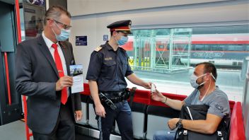Polizeibeamter mit ÖBB-Zugbegleiter im Gespräch mit Reisenden